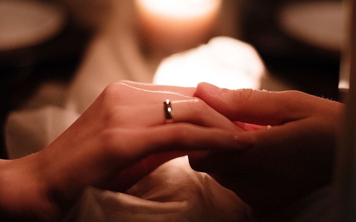 Two people holding hands with a wedding ring visible